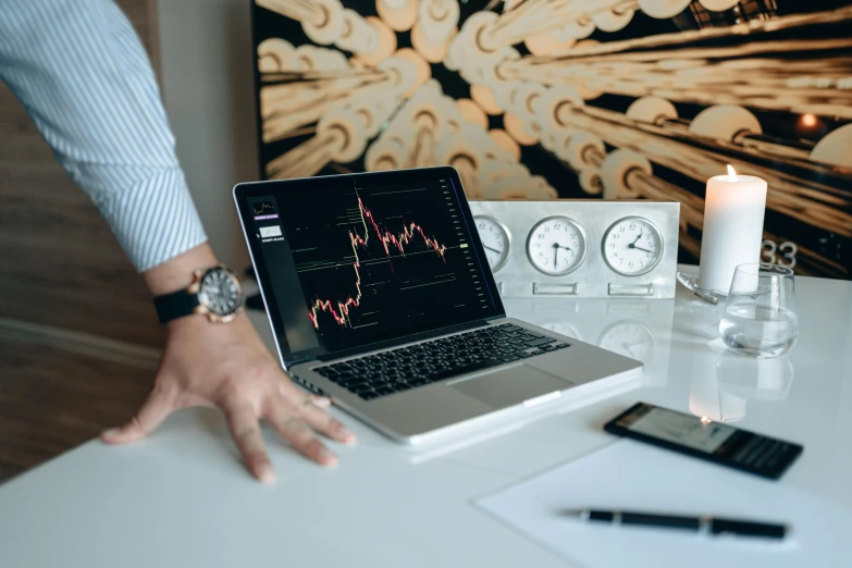 a laptop computer sitting on top of a white desk, trending on pexels, analytical art, currency symbols printed, lachlan bailey, displaying stock charts, ( 3 1