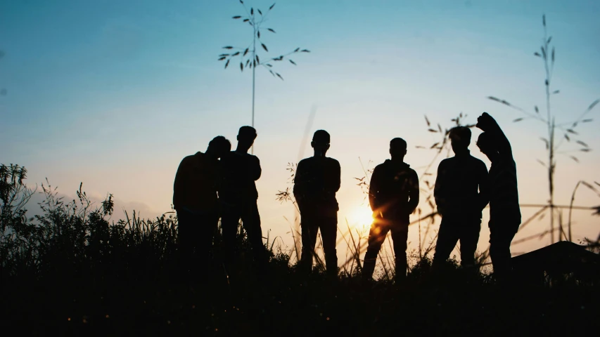 a group of men standing on top of a grass covered field, a picture, by Niko Henrichon, pexels contest winner, silhouette :7, band promo photo, evening sunlight, profile image