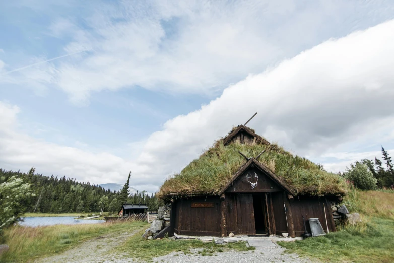 a small building with grass on top of it, by Jessie Algie, trending on unsplash, hurufiyya, wearing viking clothes, roof with vegetation, touring, conde nast traveler photo