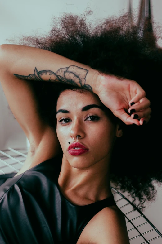 a woman with a tattoo on her arm, trending on pexels, renaissance, long afro hair, laying down, red lips, ashteroth