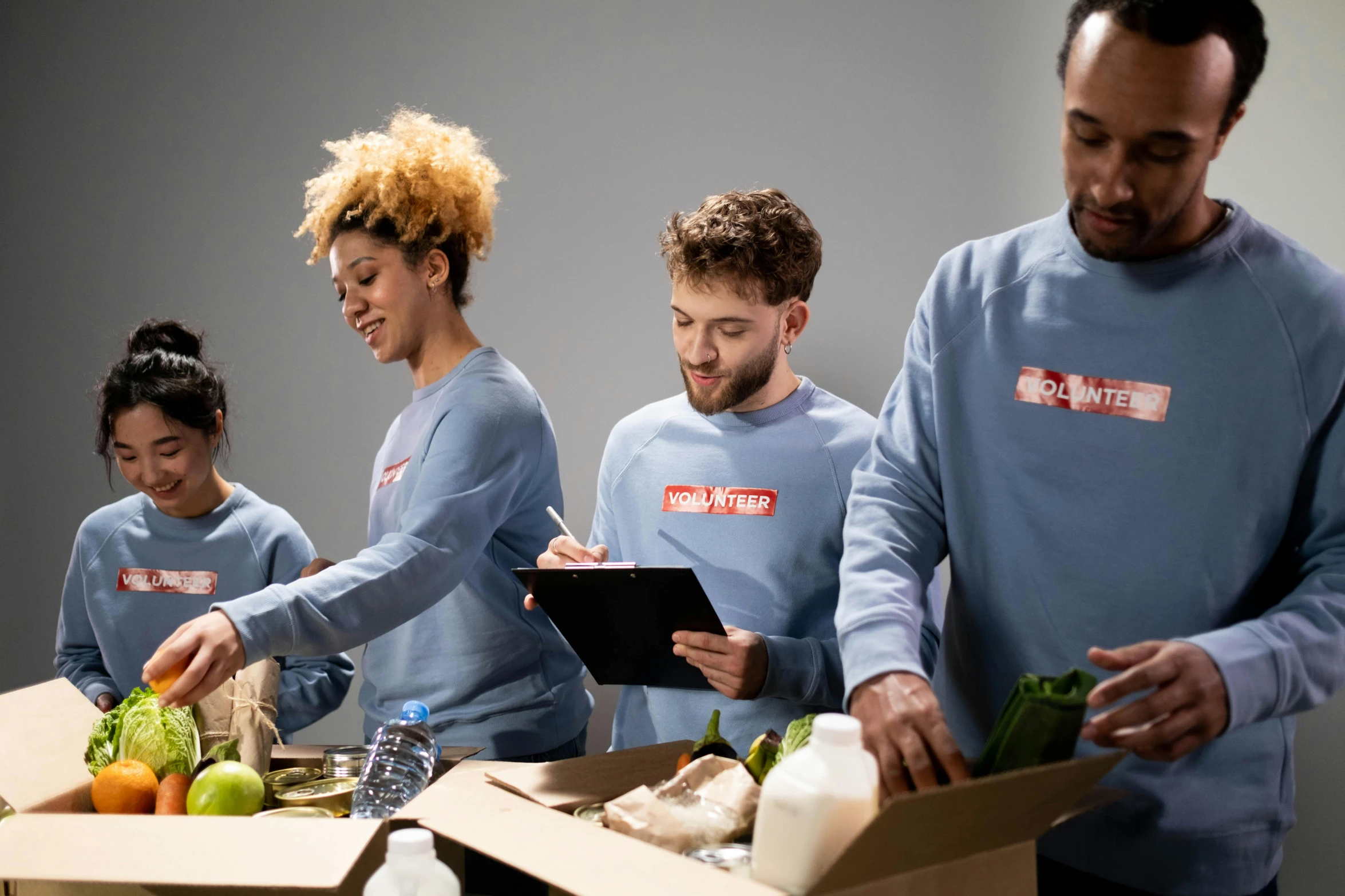 a group of people standing around a box of food, profile image, working hard, grey, extra crisp image