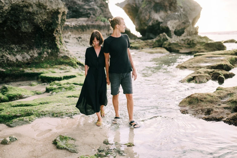 a man and a woman walking on a beach, pexels contest winner, renaissance, casual black clothing, rock pools, bali, in australia