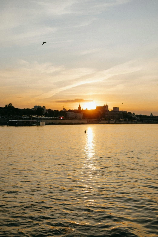 the sun is setting over a body of water, prague in the background, minimalist, golden hour photograph, cambodia