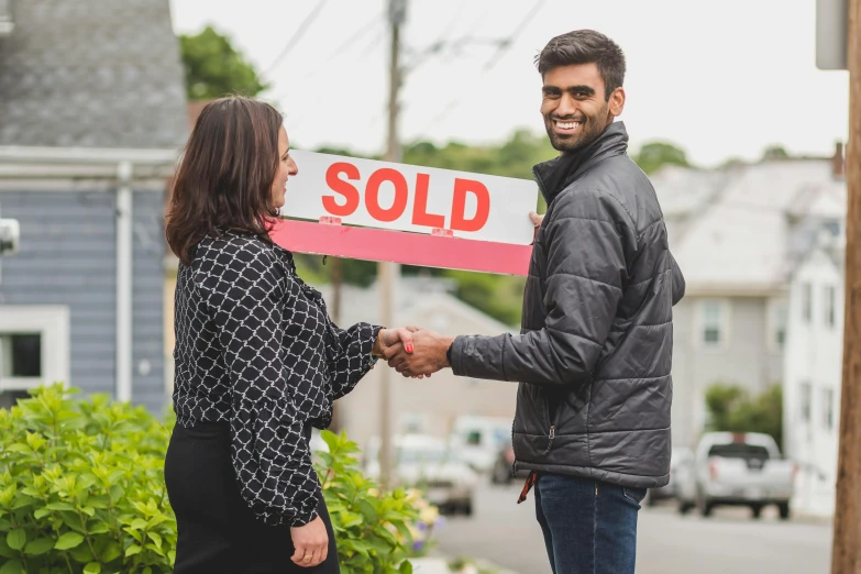 a man and woman shaking hands in front of a sold sign, a photo, pexels contest winner, hurufiyya, standing outside a house, square, profile image, colour photograph