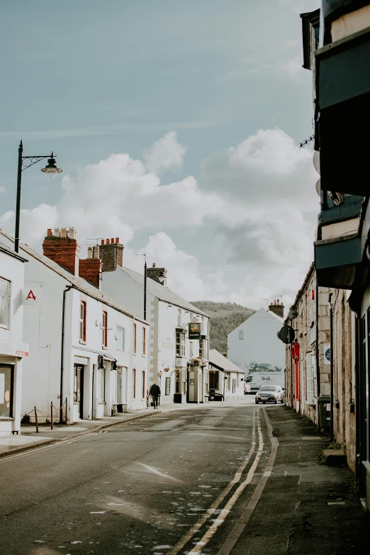 a narrow street lined with white buildings under a blue sky, by Bedwyr Williams, black mountains, unsplash photography, shop front, grey sky