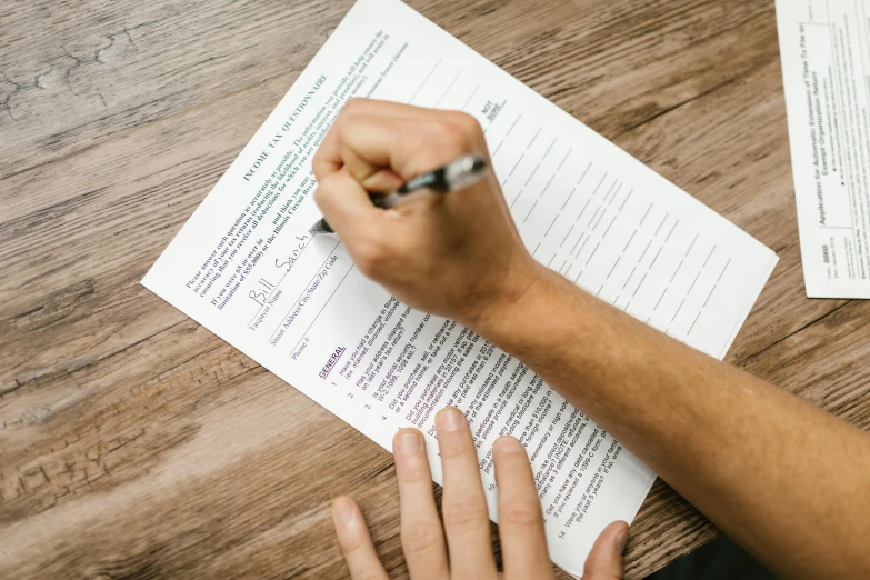 a person writing on a piece of paper with a pen, on a wooden table, acupuncture treatment, thumbnail, max dennison