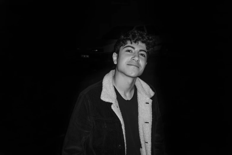 a black and white photo of a man in a jacket, an album cover, pexels, male teenager, andrew gonzalez, glowing, ✨🕌🌙