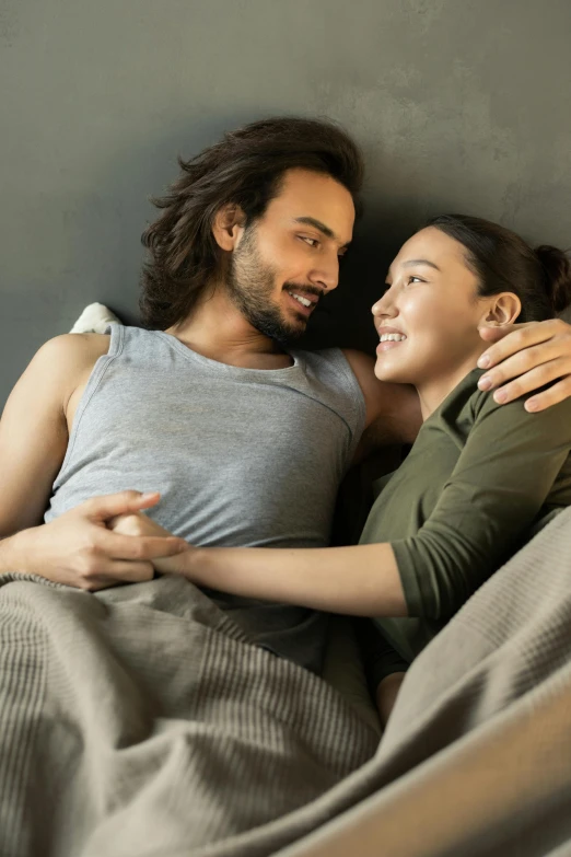 a man and woman laying in bed next to each other, a stock photo, trending on pexels, smiling at each other, jesus hugging a woman, asian descent, concerned