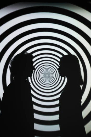 two people standing next to each other in a tunnel, by Victor Vasarely, interactive art, spirals in eyes, 1 9 7 0 s film, silhoutte, empathy machines