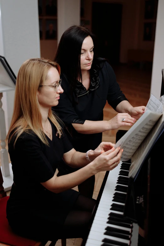 a couple of women that are sitting in front of a piano