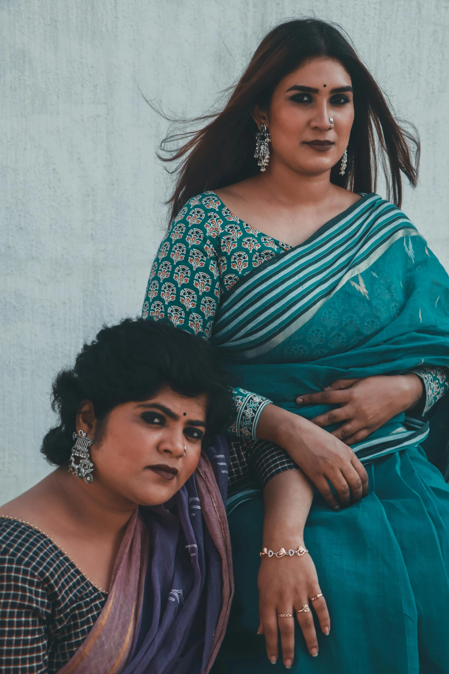 a couple of women sitting next to each other, an album cover, wearing a sari, monochromatic teal, queer woman, plus-sized