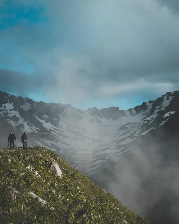 a couple of people standing on top of a mountain, in a valley