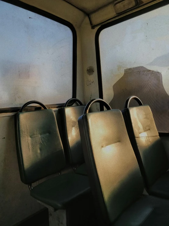 a group of empty seats sitting next to each other, dirty windows, sun overhead, portrait of a slightly rusty, high-quality photo