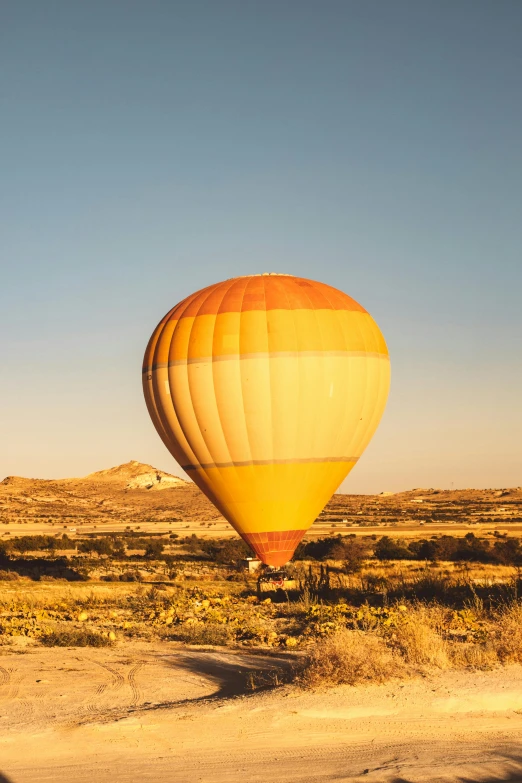 a hot air balloon that is flying in the sky, by Daren Bader, wandering the desert landscape, shades of yellow, turkey, nice afternoon lighting