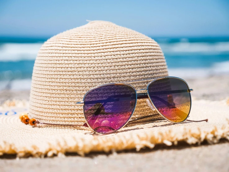 a hat and sunglasses on a beach with the ocean in the background, pexels contest winner, heat shimmering, thumbnail, vibrantly colored, summer sunlight