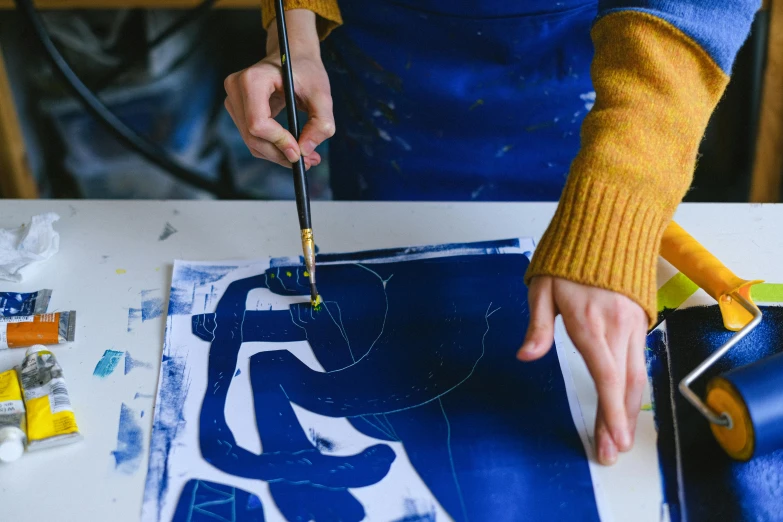 a close up of a person holding a pair of scissors, a silk screen, inspired by Henri Matisse, trending on pexels, cyanotype, paints mixing, hand on table, lettering