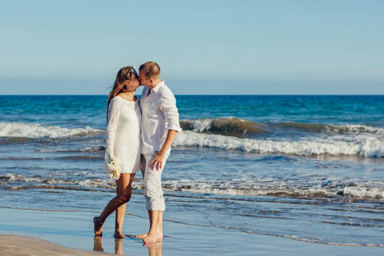 a man and woman standing on a beach next to the ocean, marbella, profile image, kiss, test