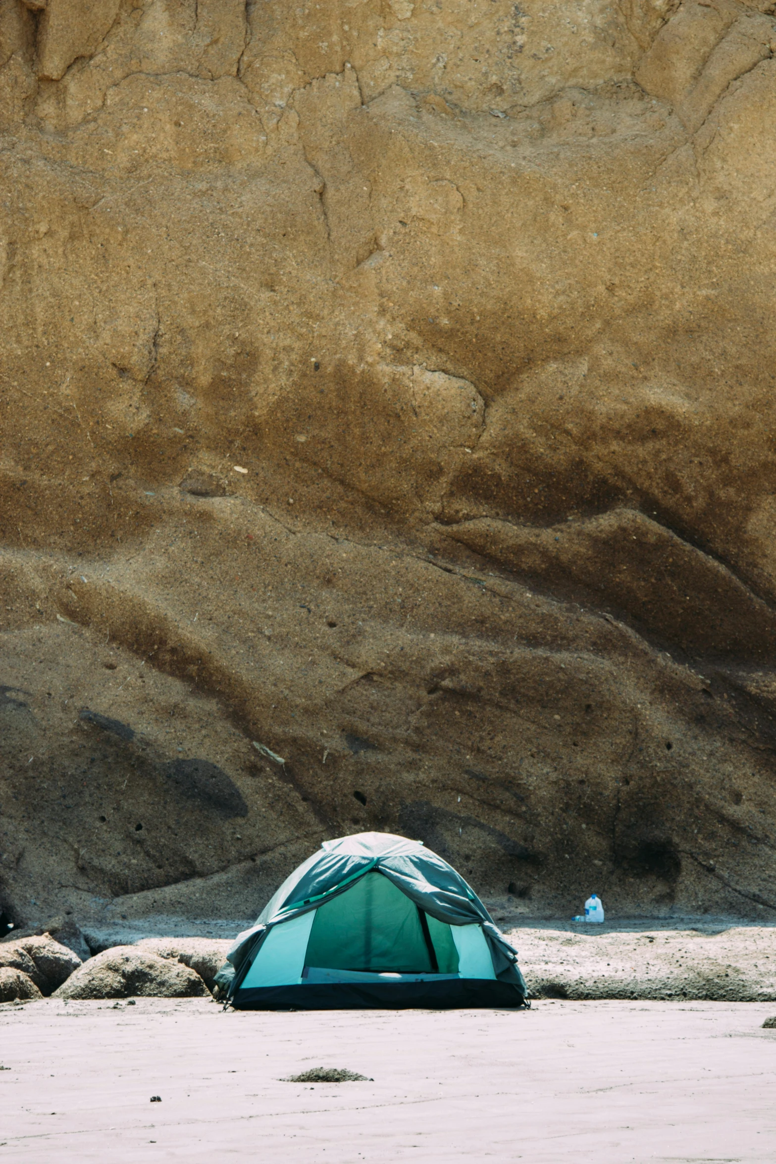 a green tent sitting on top of a sandy beach, a photo, by Elsa Bleda, trending on unsplash, renaissance, natural cave wall, detailed terrain texture, photo taken on fujifilm superia, brown