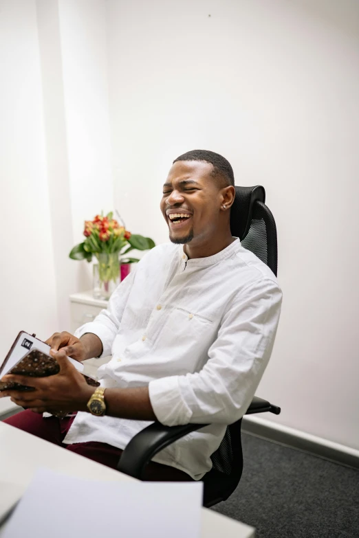 a man sitting at a desk in front of a laptop computer, inspired by Edward Okuń, happening, mutahar laughing, holding notebook, dentist, in a comfortable chair