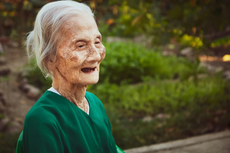 a close up of a person wearing a green shirt, pexels contest winner, old lady screaming and laughing, lush surroundings, looking off to the side, very old