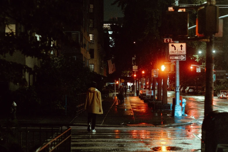 a person walking across a street at night, inspired by Elsa Bleda, unsplash contest winner, realism, yellow raincoat, new york streets, humid evening, 8k resolution”