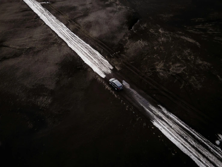 an aerial view of a car driving down a road, by Jacob Toorenvliet, unsplash contest winner, auto-destructive art, desolate arctic landscape, made of tar, white on black, dark and dusty