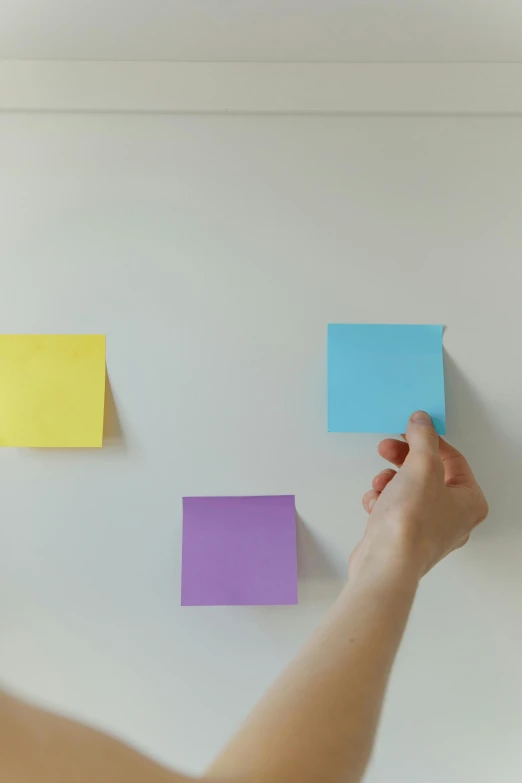 a woman standing in front of a whiteboard covered in post it notes, pexels, square shapes, color footage, on a pale background, hand