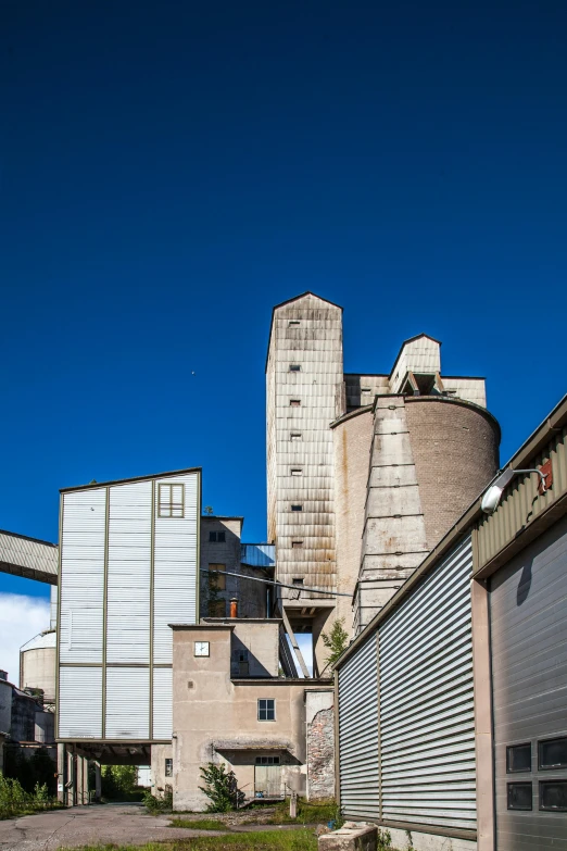 a red fire hydrant sitting on the side of a road, by Andries Stock, brutalism, silo, panorama, brown, blue