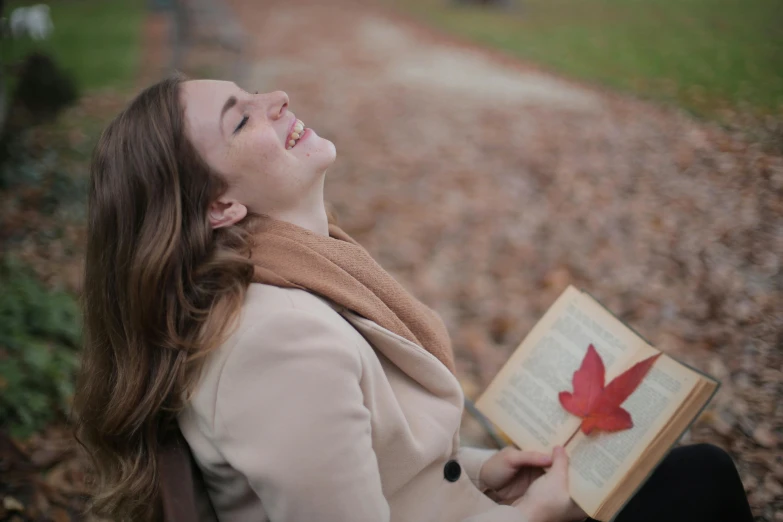 a woman sitting on a bench reading a book, pexels contest winner, happening, falling leaves, cheeky smile with red lips, profile image, 1 5 6 6