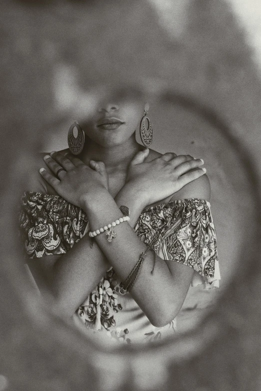 a black and white photo of a woman in a mirror, inspired by Gordon Parks, intricate african jewellery, 1980s photograph, hands crossed, studio medium format photograph