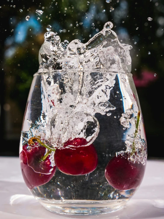 a glass of water with cherries in it, by Cherryl Fountain, pexels contest winner, escaping air bubbles, mid view, high quality product image”