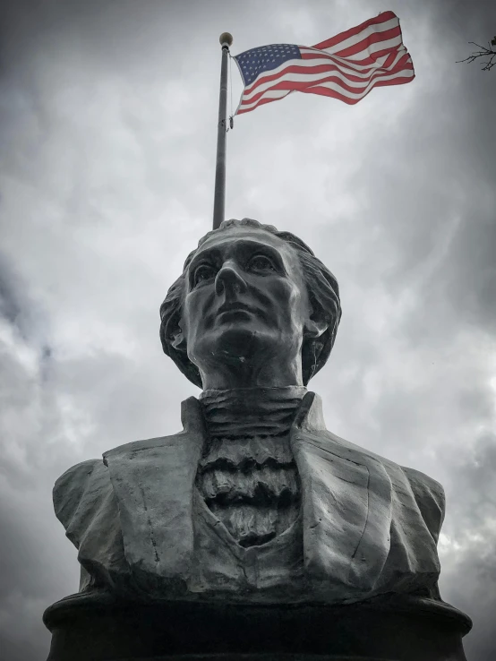 a statue of abraham lincoln with an american flag in the background, inspired by Patrick Henry Bruce, unsplash, gray skies, instagram story, puerto rico, looking up at camera