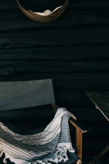 a hammock sitting on top of a wooden chair, an album cover, unsplash, modernism, dark photo, cabin, folds of fabric, low quality photo