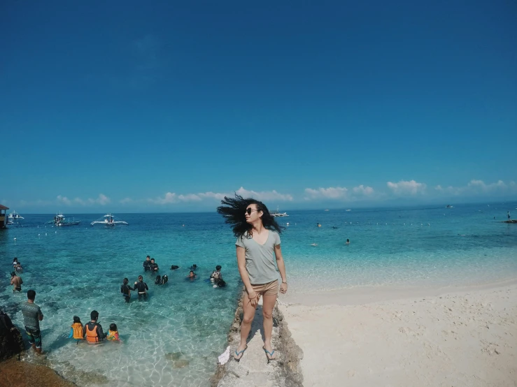 a woman standing on top of a sandy beach, by Robbie Trevino, reefs, clear sunny day, group photo, zenra taliyah