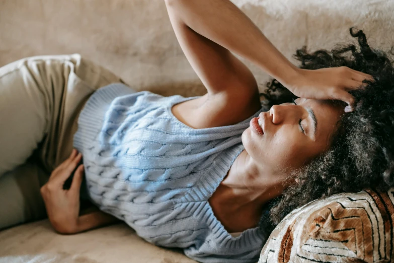 a woman laying on a couch with her eyes closed, trending on pexels, an ahoge stands up on her head, sickness, woman with braided brown hair, african american young woman