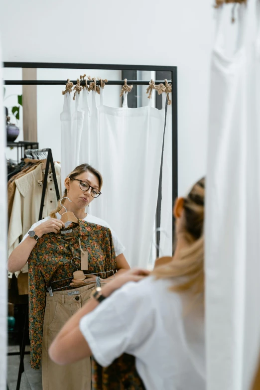 a woman that is standing in front of a mirror, wearing clothes