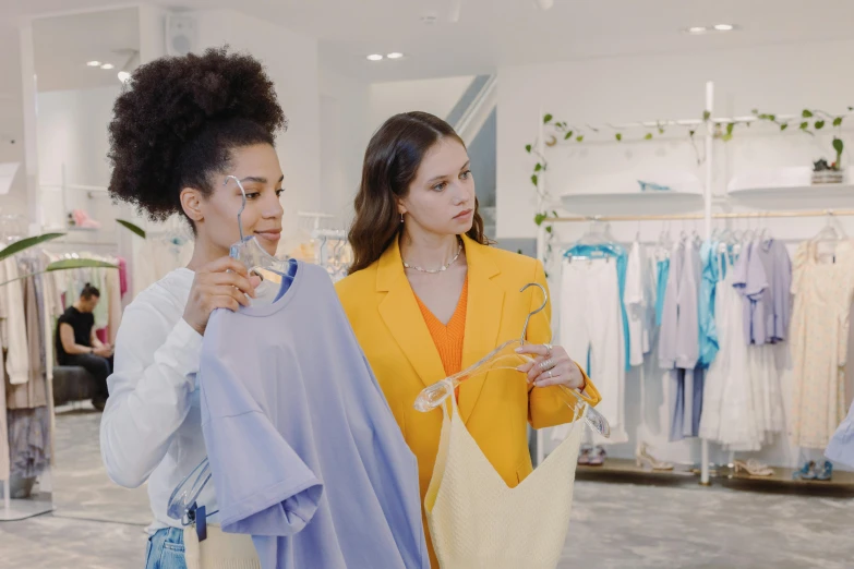 two women standing next to each other in a clothing store, trending on pexels, happening, in blue and yellow clothes, calmly conversing 8k, thumbnail, white hue