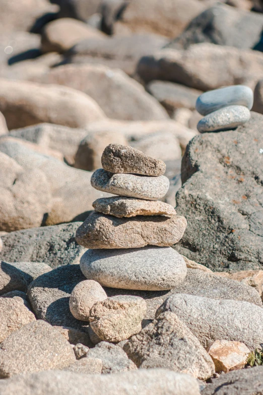 a pile of rocks sitting on top of a rocky beach, lynn skordal, petite, circles, stone bricks