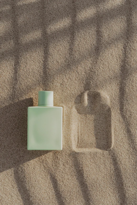 a bottle of perfume sitting on top of a sandy beach, inspired by Raoul De Keyser, unsplash, conceptual art, gradient pastel green, rectangle, issey miyake, overview