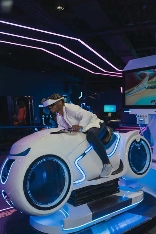 a man sitting on top of a futuristic car, a hologram, inspired by Hendrick Cornelisz Vroom, afrofuturism, gaming room, softplay, riding a futuristic motorcycle, racecar