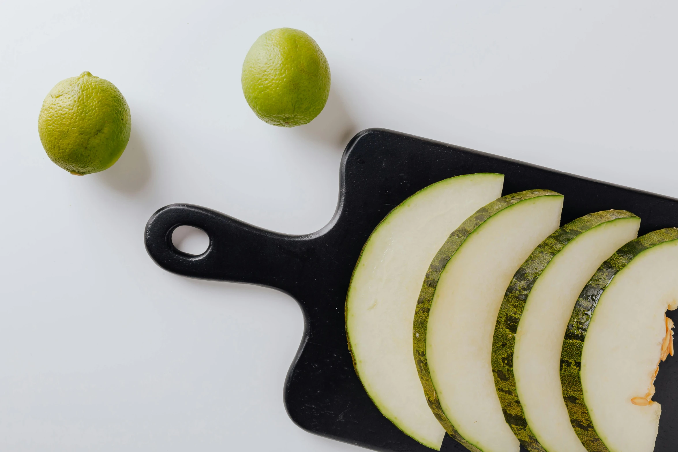 a cutting board with slices of melon and limes, unsplash, black, very hazy, background image, petite pear slim figure