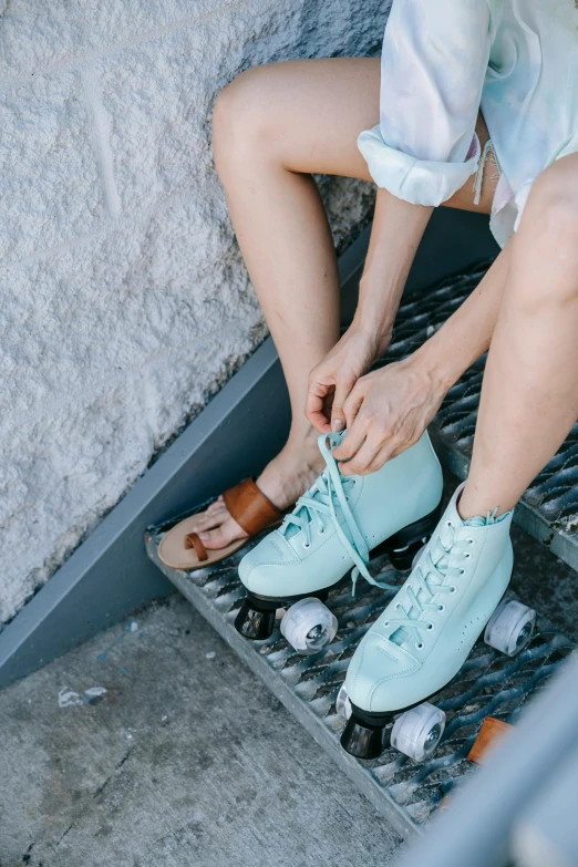 a woman is tying her shoes on the steps, a colorized photo, trending on pexels, soft blues and greens, roller skating, pale blue outfit, milk