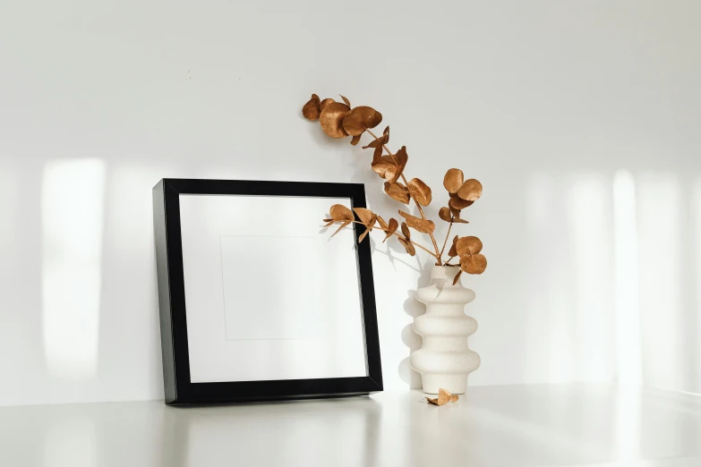 a white vase sitting on top of a table next to a picture frame, pexels contest winner, square shapes, white background : 3, architectural, background image