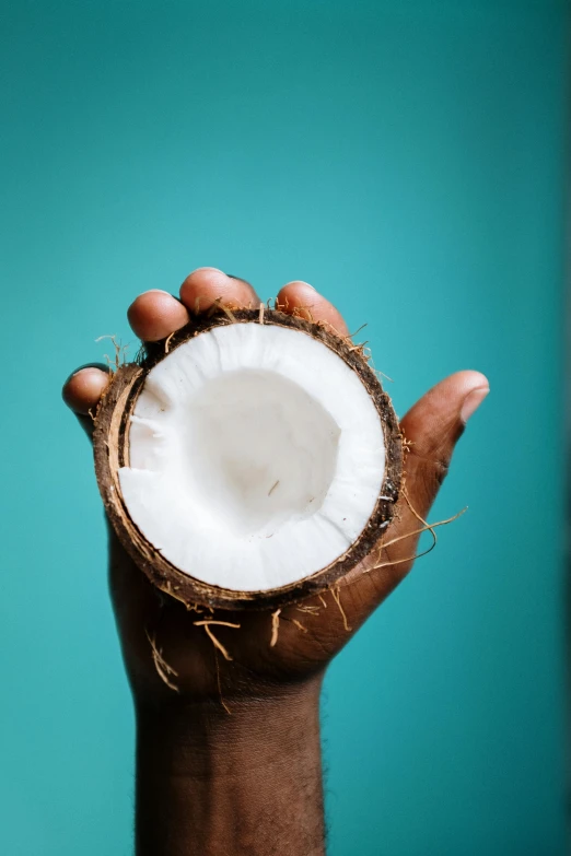 a person holding a coconut in their hand, an album cover, by Matthias Stom, trending on unsplash, full frame image, multiple stories, dark-skinned, half blue