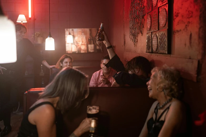 a group of people that are sitting in a room, by Lee Loughridge, pexels, happening, local bar, cinematic and dramatic red light, straya, a still of a happy