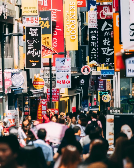 a crowd of people walking down a street next to tall buildings, by Jang Seung-eop, trending on unsplash, colorful signs, korean woman, lots of signs and shops, square