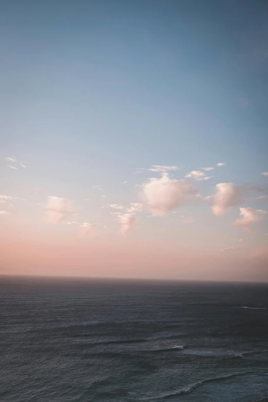 a large body of water next to a beach, an album cover, inspired by Elsa Bleda, unsplash, romanticism, light pink clouds, south african coast, horizon view, above the clouds