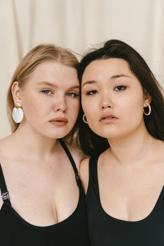 a couple of women standing next to each other, inspired by Wang Duo, trending on unsplash, renaissance, huge earrings and queer make up, alluring plus sized model, soft flawless pale skin, south east asian with round face