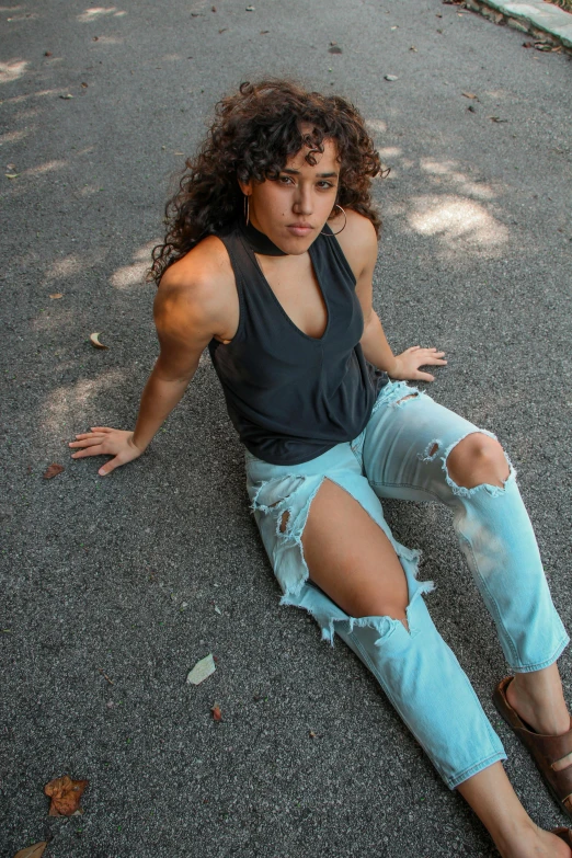 a woman sitting on the ground next to a skateboard, by Washington Allston, trending on pexels, renaissance, wearing a low cut tanktop, curly hair, teal tones, fighter pose