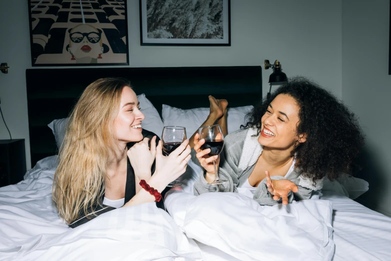 a couple of women laying in bed next to each other, trending on pexels, happening, enjoying a glass of wine, sydney sweeney, walking down, with black